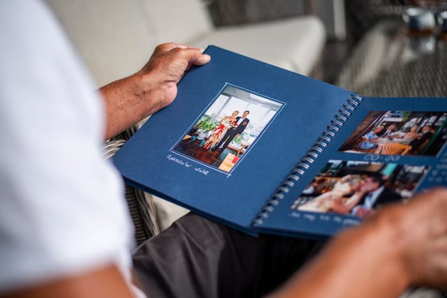 Nærbilde av bryllupsbilde i fotoalbum. Marit i lys kjole med blomstermotiv og Stein Tore i svart smoking