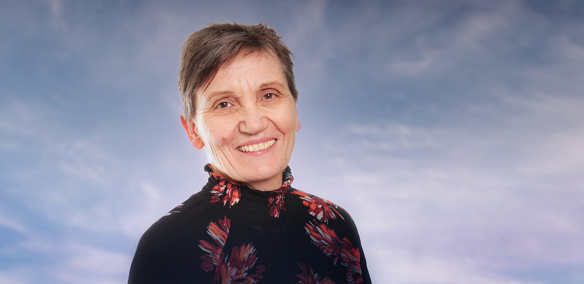 Portrettbilde av Solveig Hofvind i Kreftregisteret, med en lettskyet himmel i bakgrunnen. Foto.