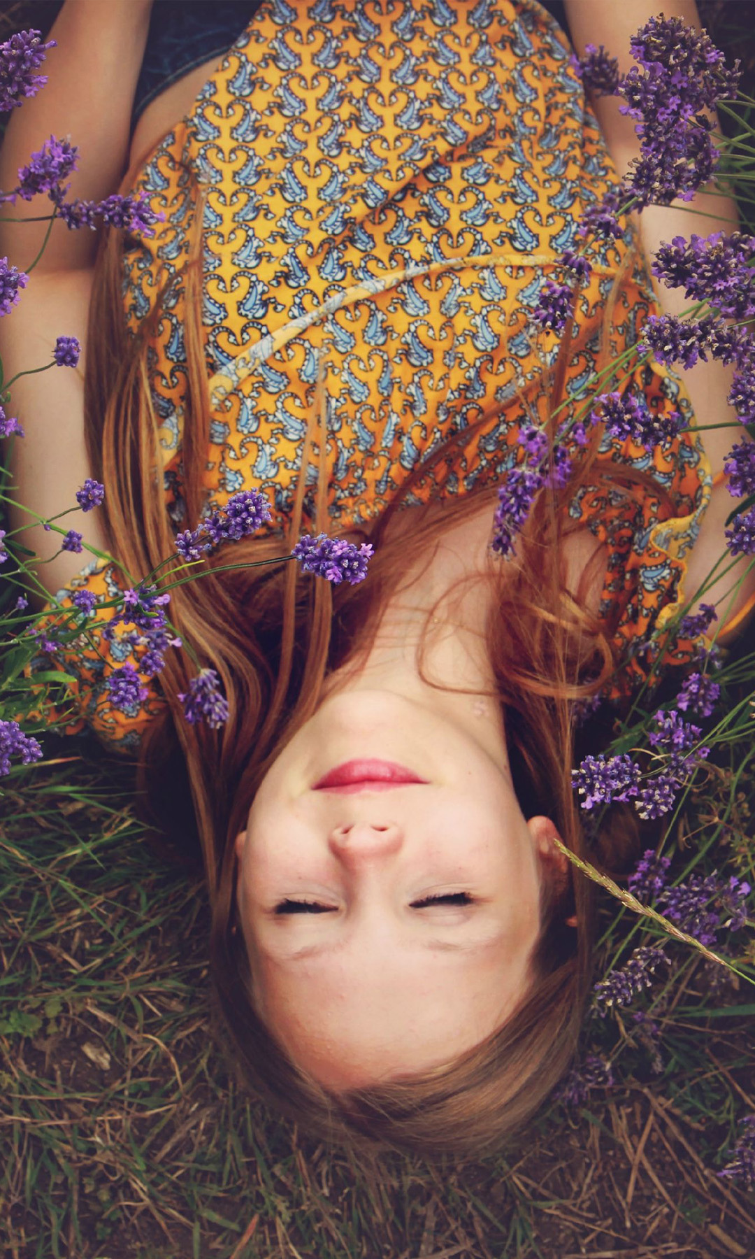 Ung kvinne ligger i blomstereng med lukkede øyne og prøver å få sove, tross smerter fra kreft. Illustrasjonsfoto.