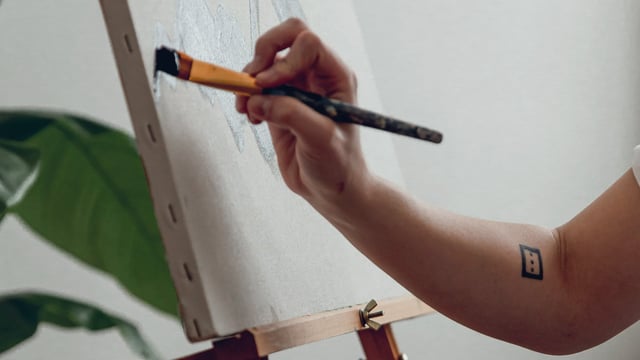 Nærbilde av en hånd som maler på et lerret for å få en pause fra tankemylder rundt metastatisk brystkreft. Illustrasjonsfoto