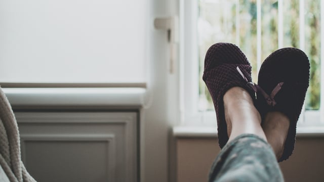 Nærbilde av to føtter med tøfler som hviler på sofakanten. Kvinnen har metastatisk brystkreft og lavt energinivå. Illustrasjonsfoto