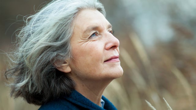 Nærbilde av kvinne med metastatisk brystkreft ute i naturen som forsøker å balansere vanskelige følelser mens hun ser opp i luften. Illustrasjonsfoto